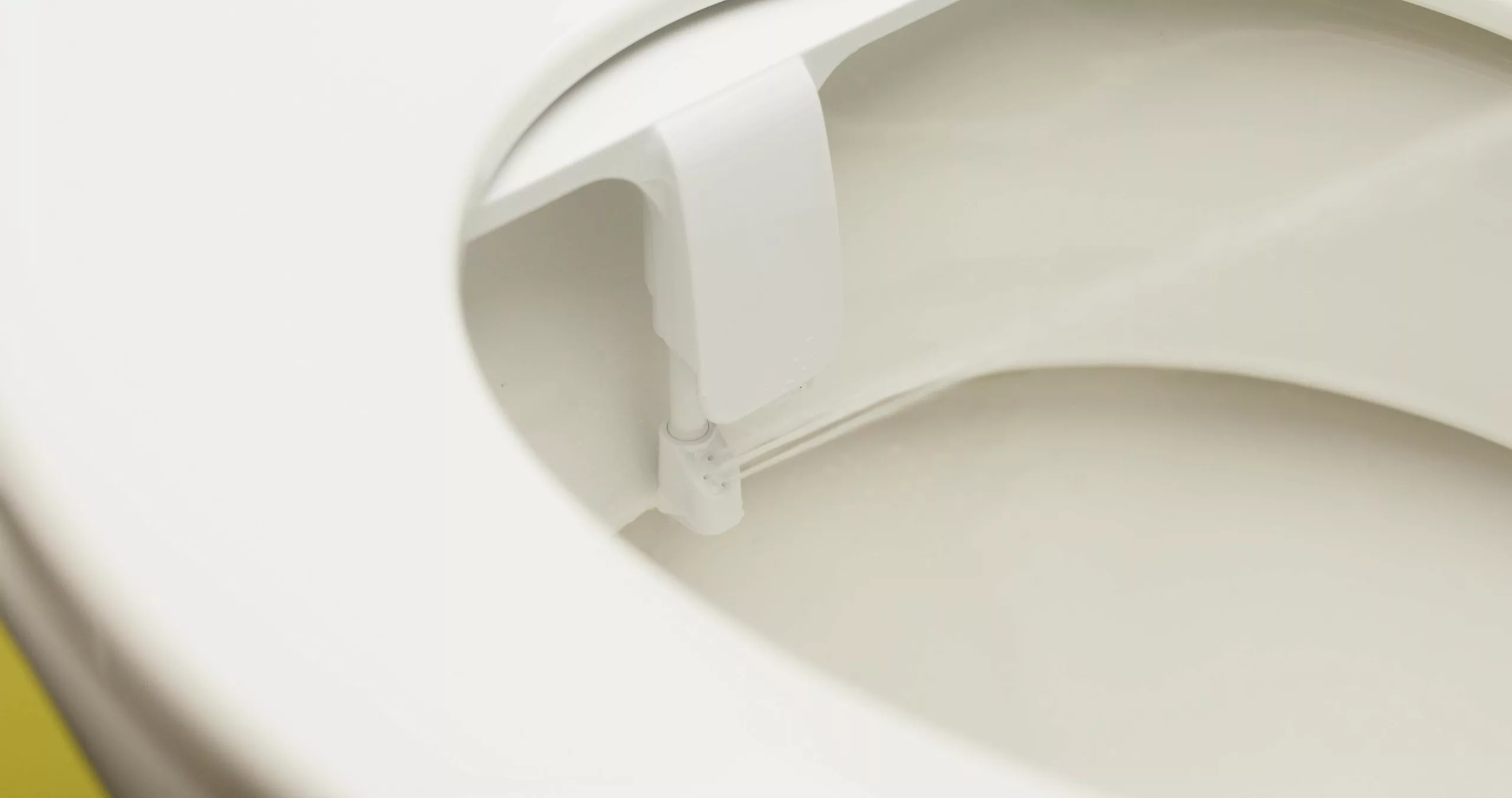 Boquilla de un adaptador de bidé lanzando el chorro de agua dentro de la taza del inodoro